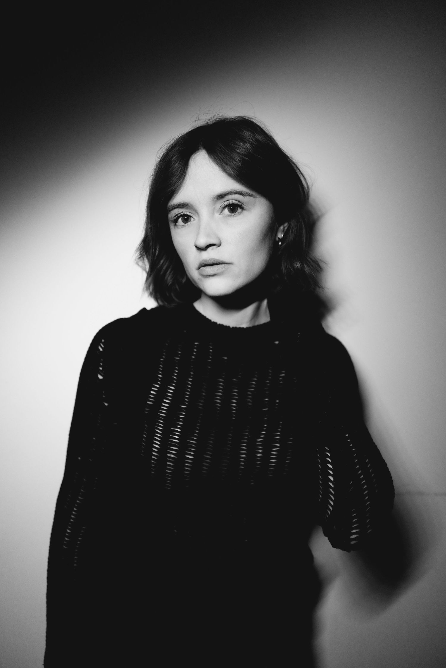 Dramatic black and white portrait series featuring moody lighting and dark clothing against a stark background.