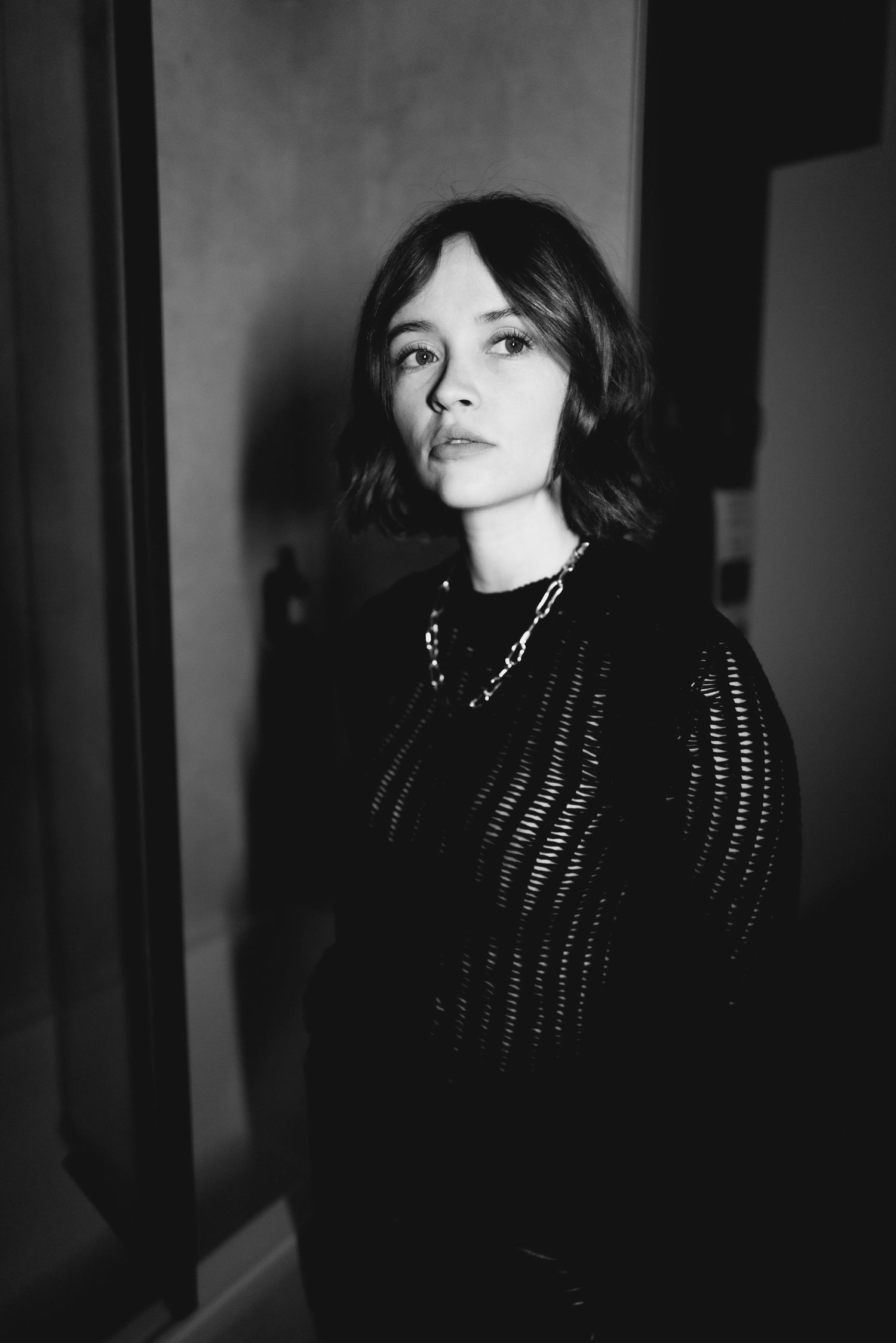 Dramatic black and white portrait series showing moody lighting and dark scarf against bookshelves.