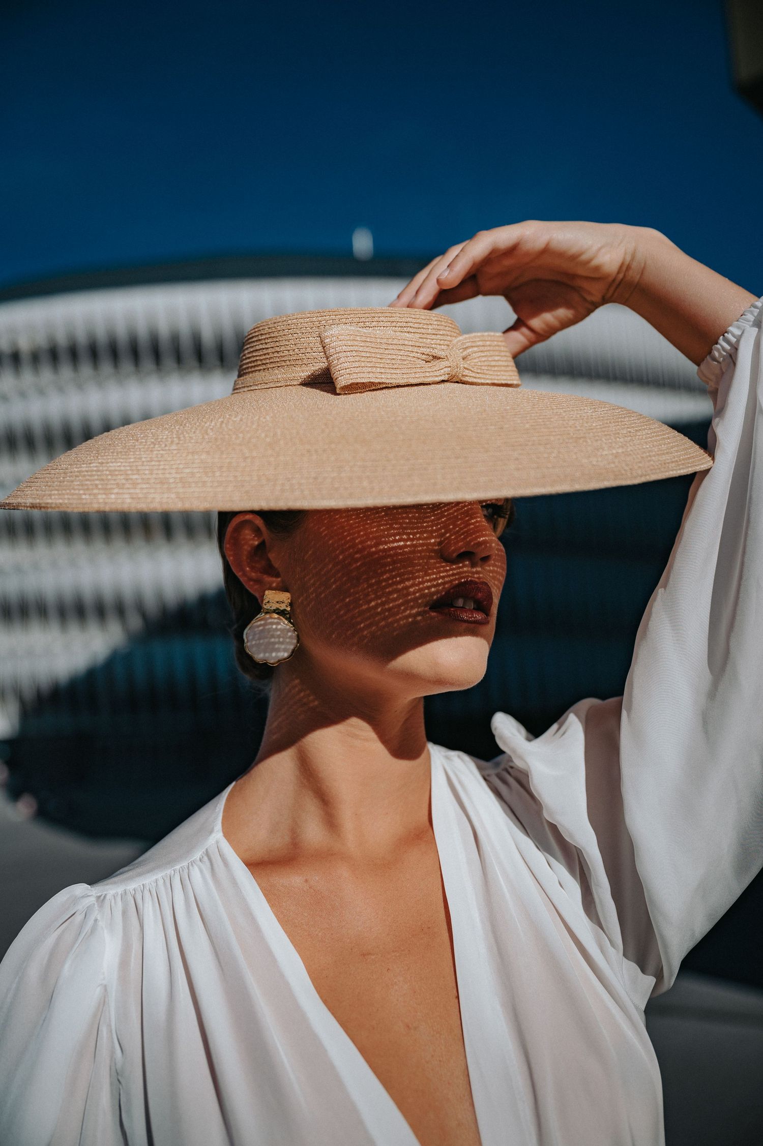 Stylish portraits featuring a wide-brimmed straw hat and flowing white dress.