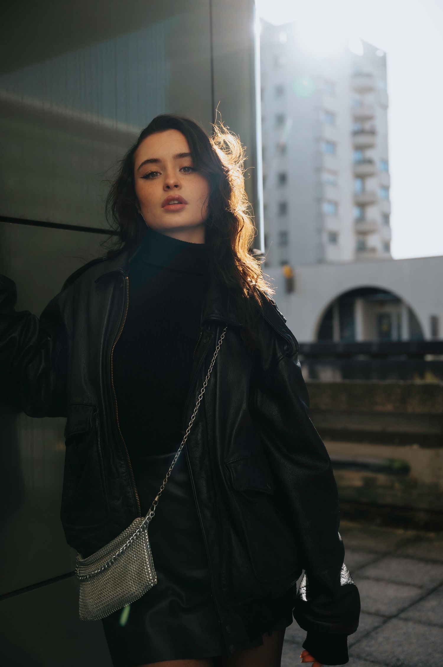 Urban fashion shots featuring a black coat and backlit cityscape.