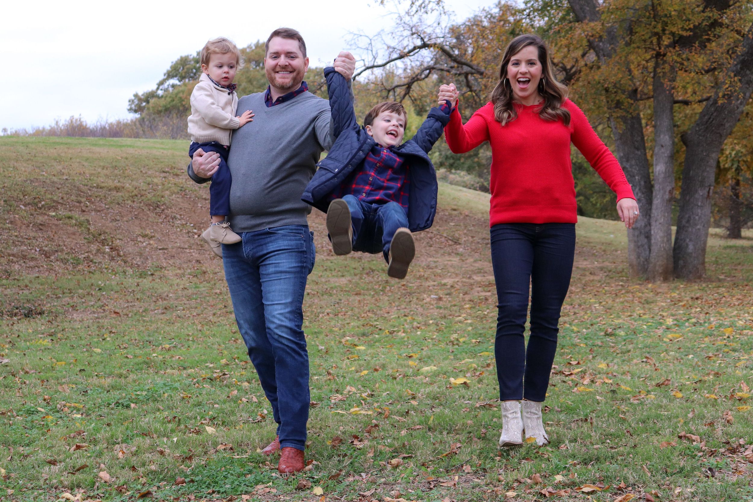 Family playing and jumping together outdoors on an autumn day.