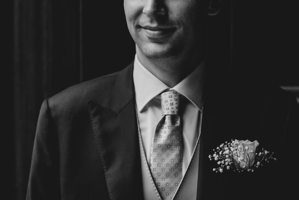 Black and white portrait of formal wedding attire and boutonniere details.