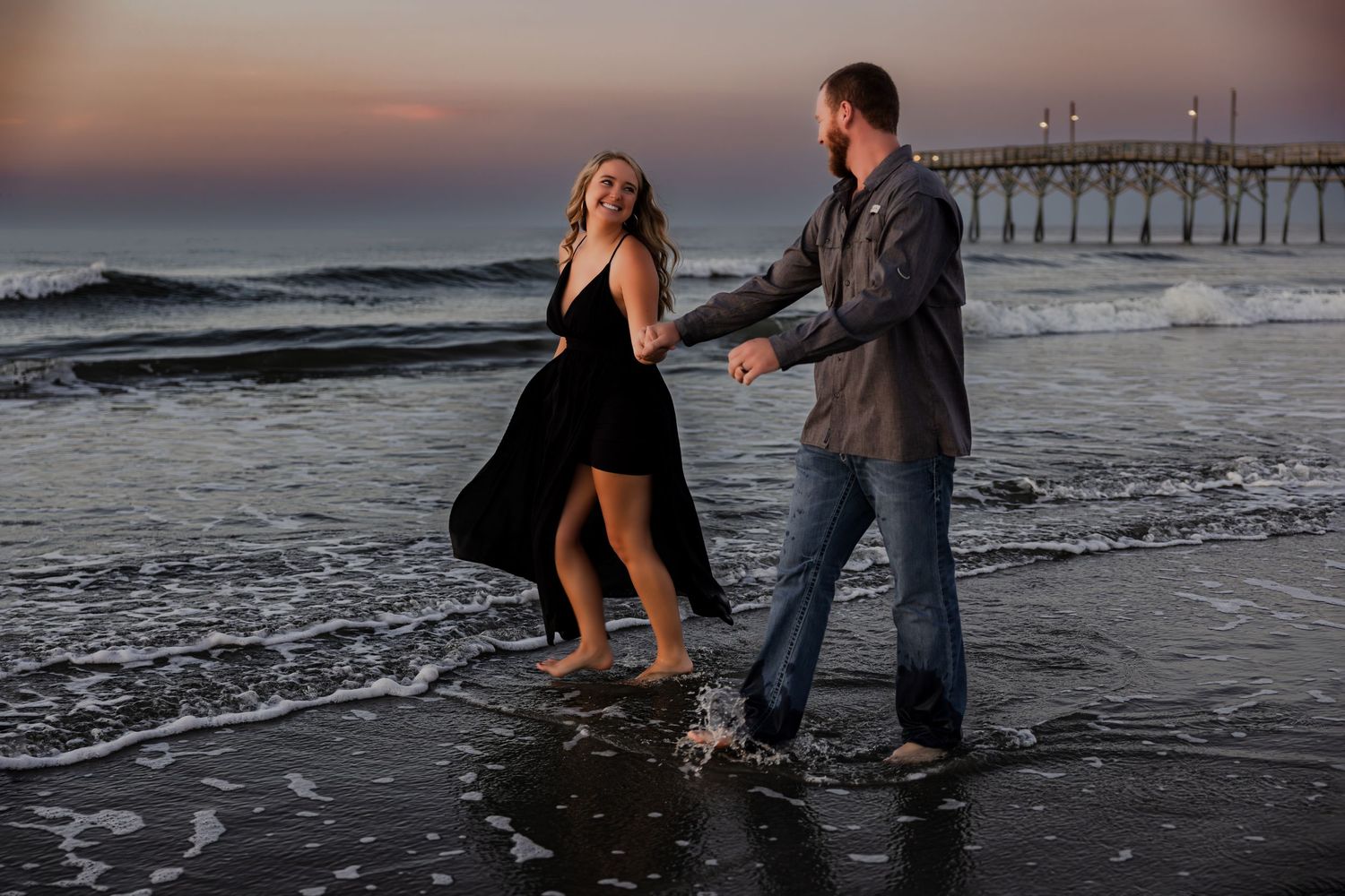 Couple photo session walking and playing along a beach shoreline at sunset in a sequence of romantic moments in North Carolina.