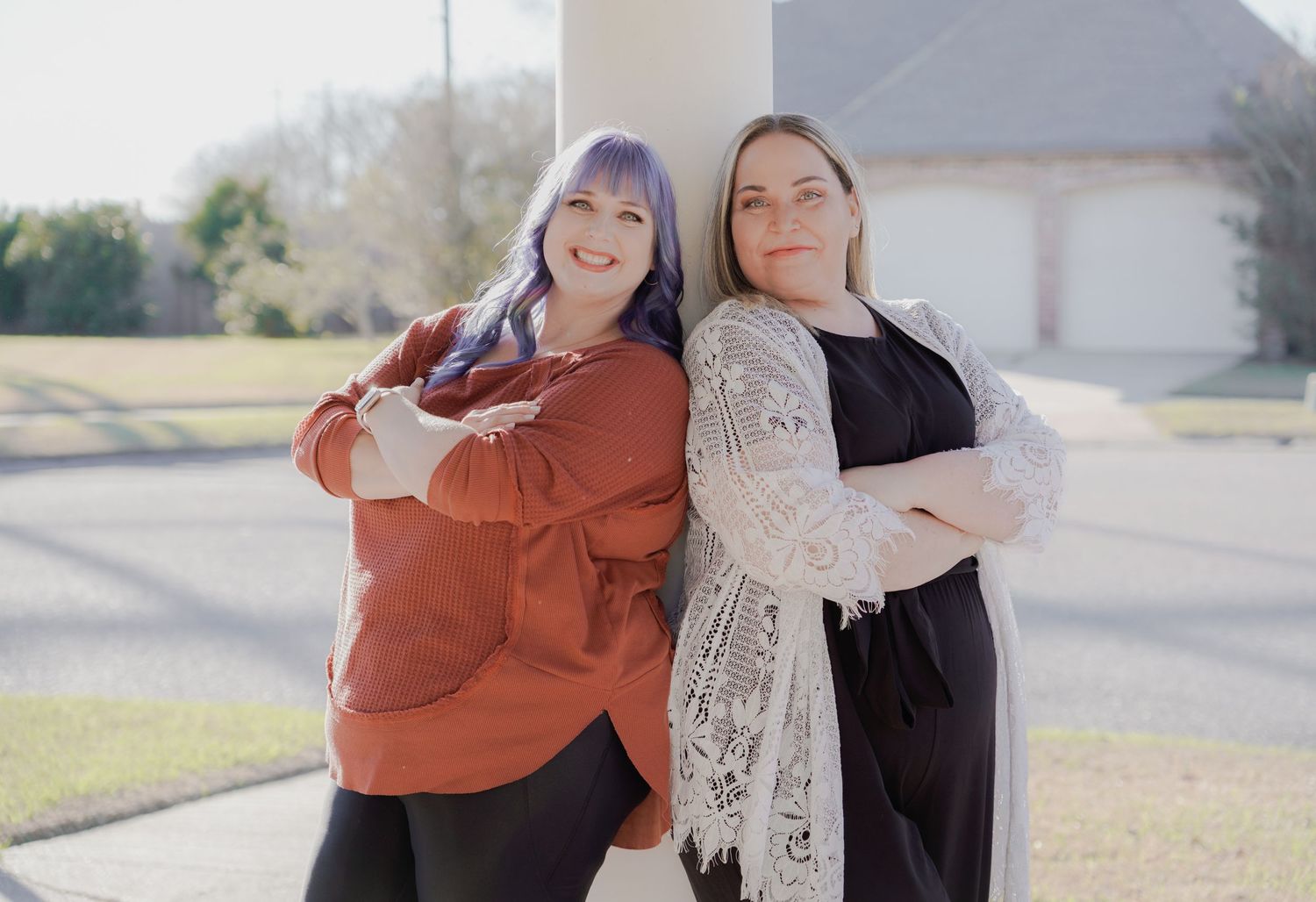 Friends embracing and smiling while standing outside in casual attire.