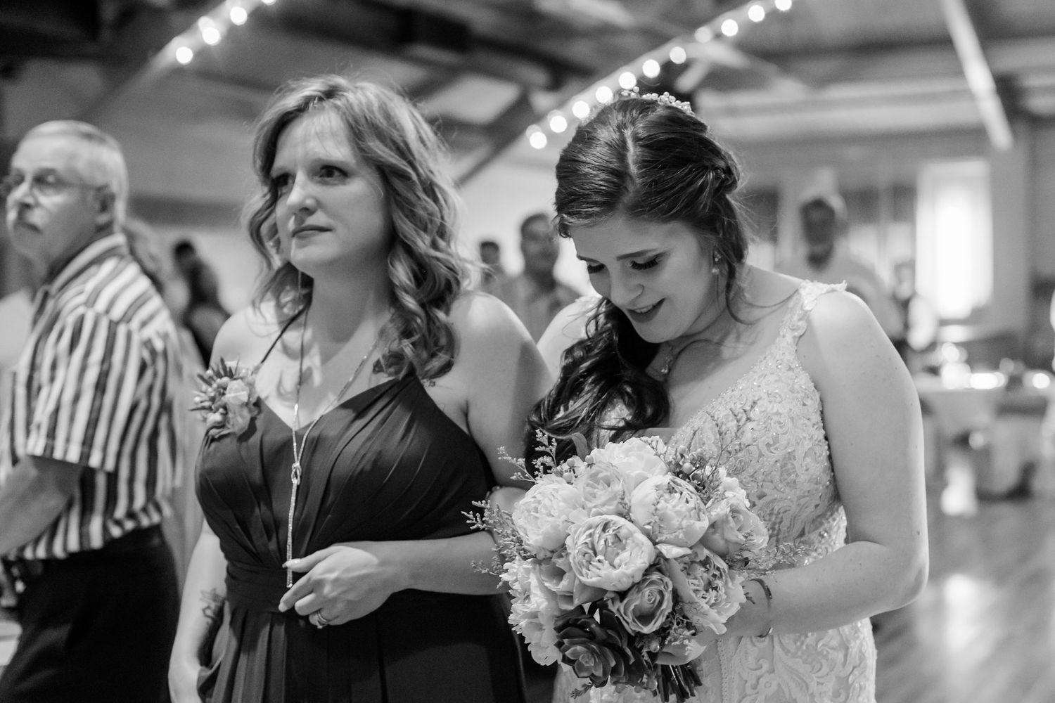 Wedding party members share emotional reactions during a special moment at an indoor ceremony.
