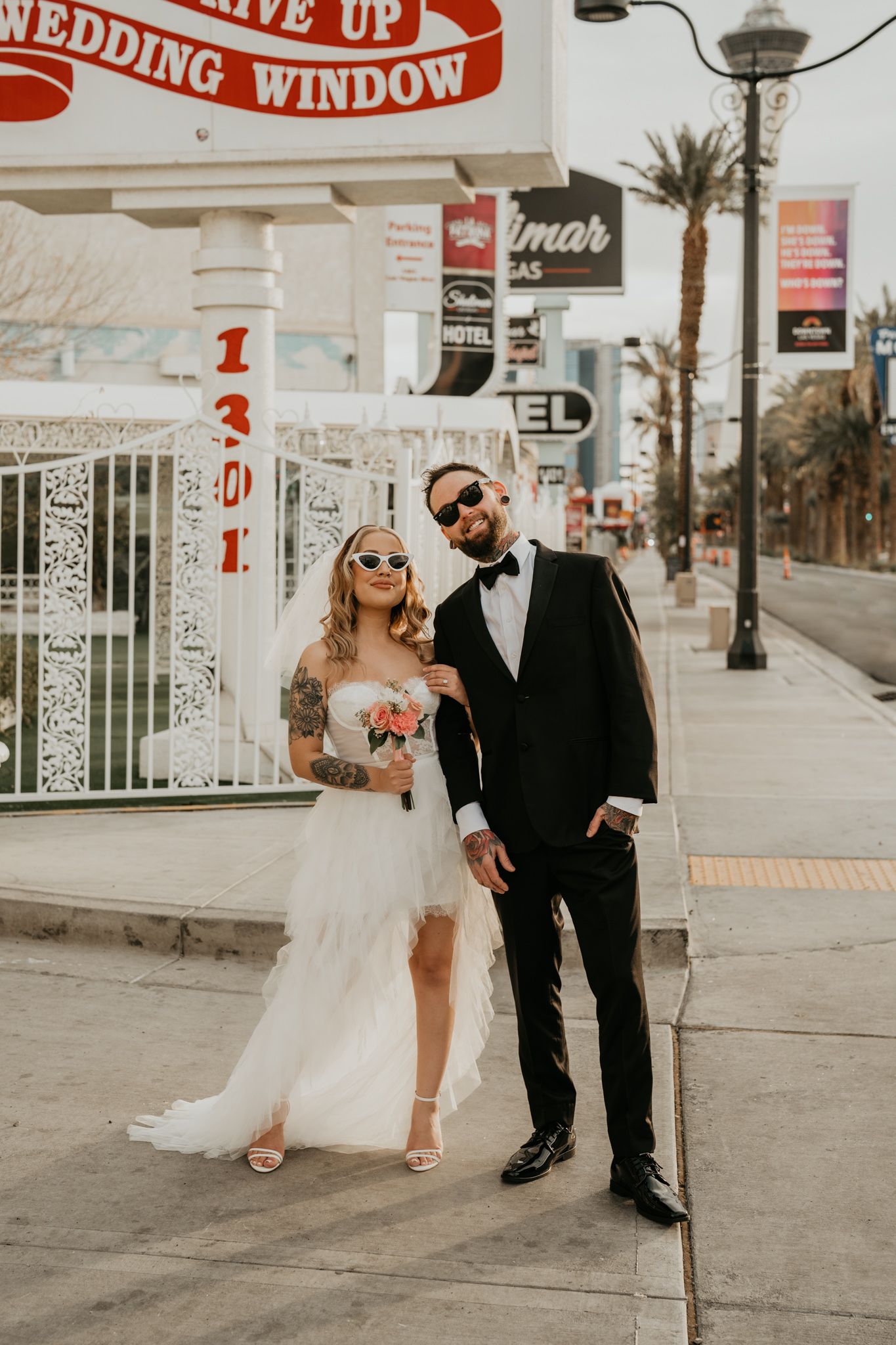 Couple poses in wedding attire outside vintage Las Vegas wedding chapel.