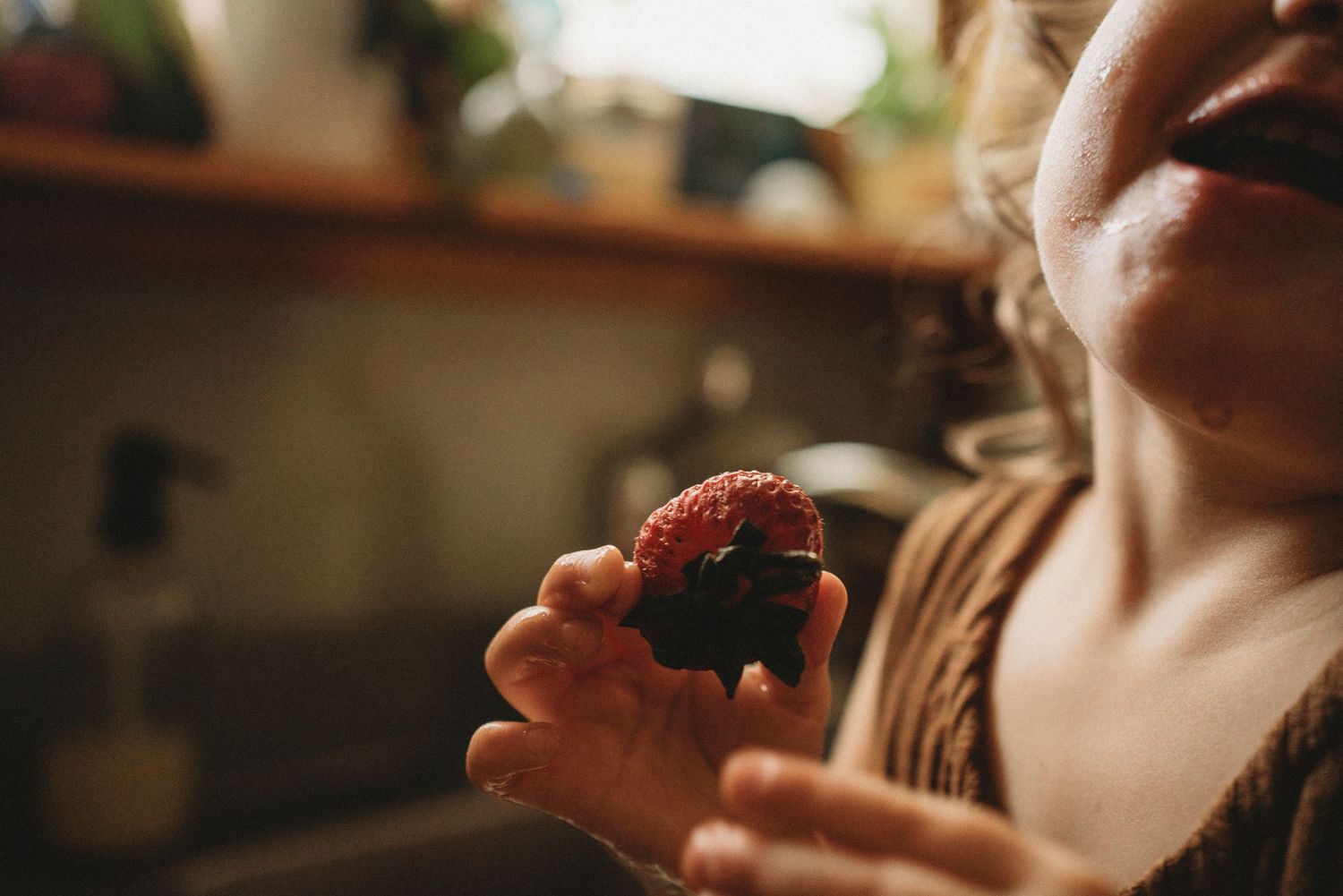Close-up shot of someone holding and eating a fresh strawberry.