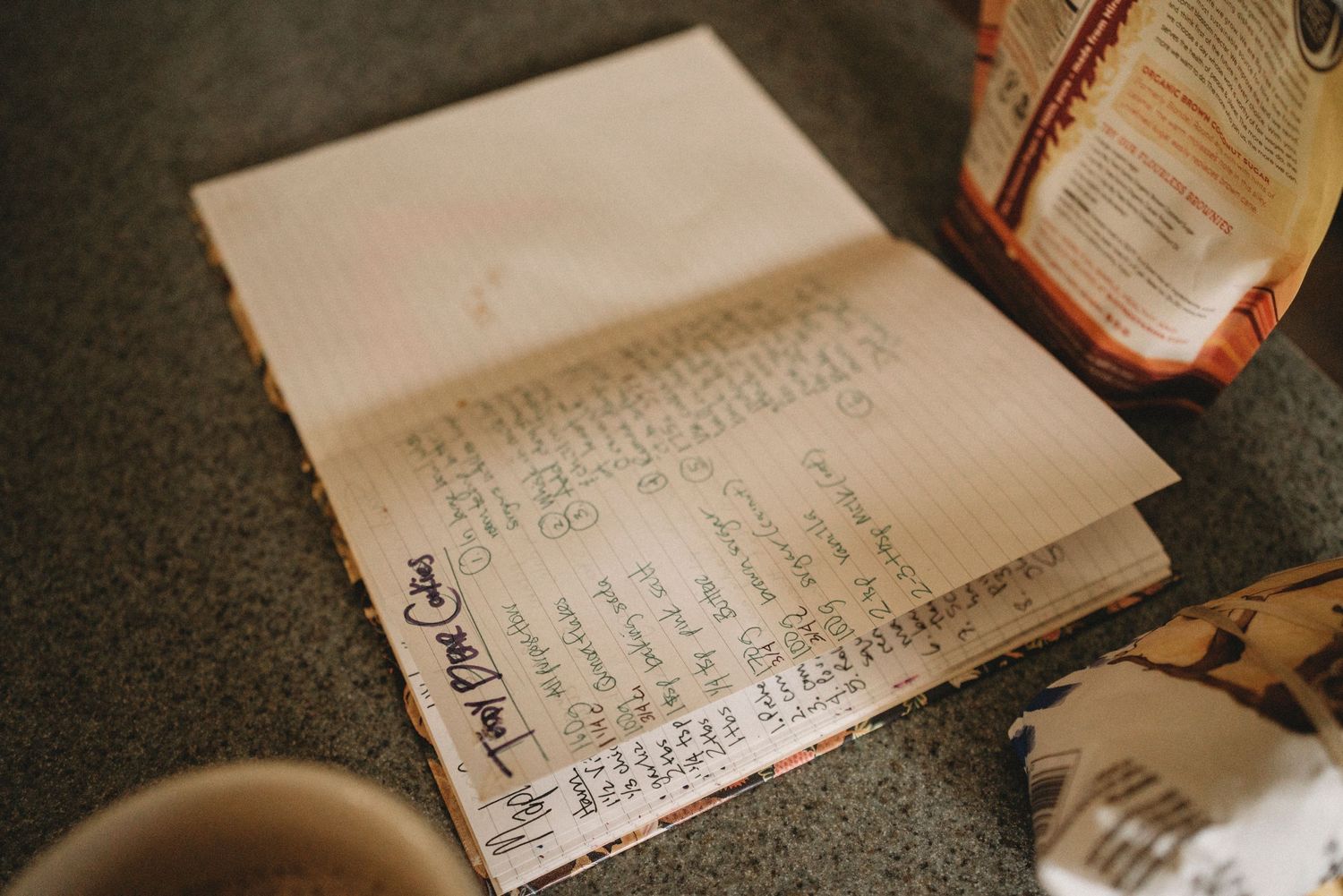 Handwritten recipe or ingredient list on paper with warm lighting.
