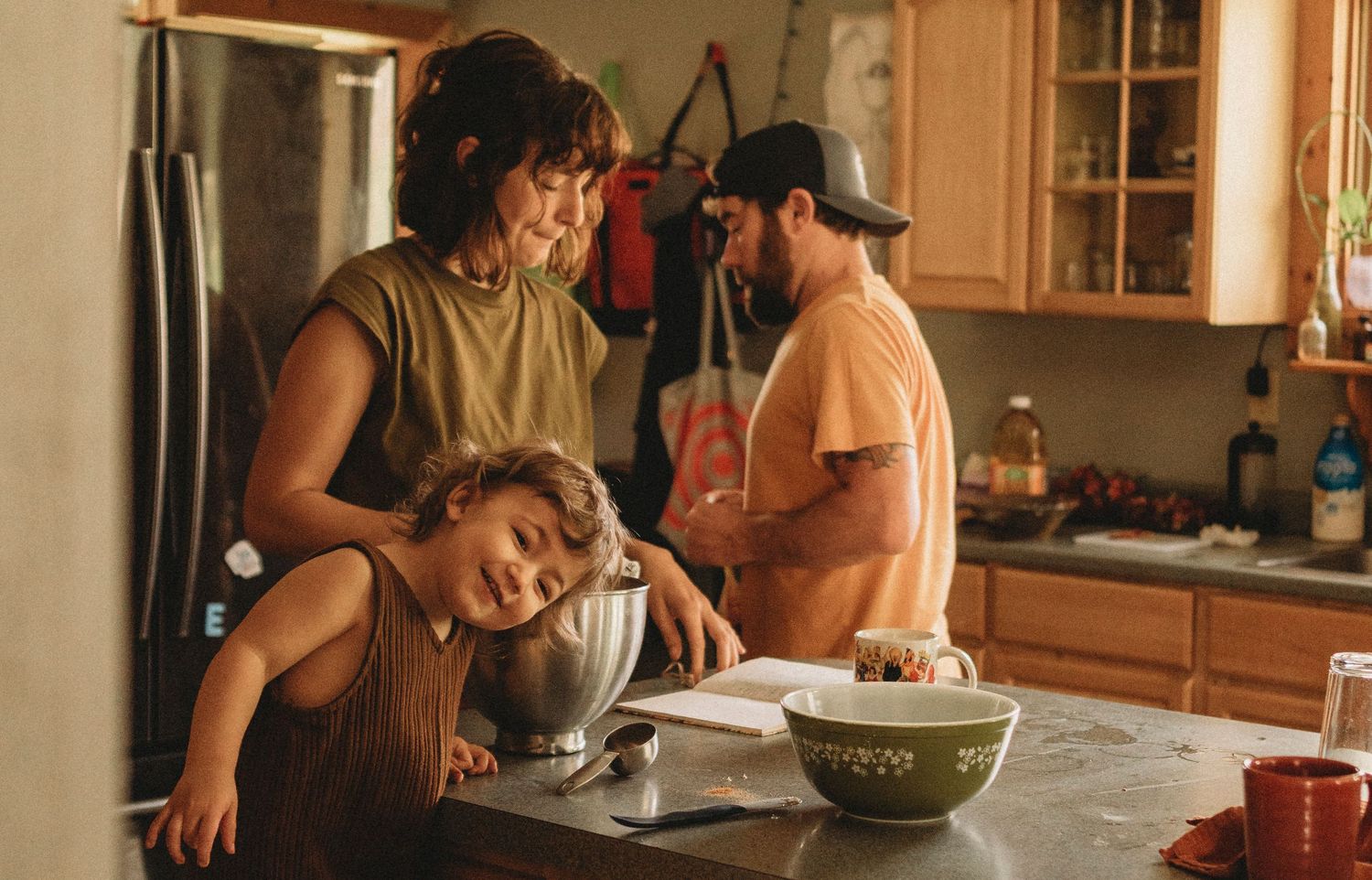 Family gathered around kitchen counter during cooking or baking activity.