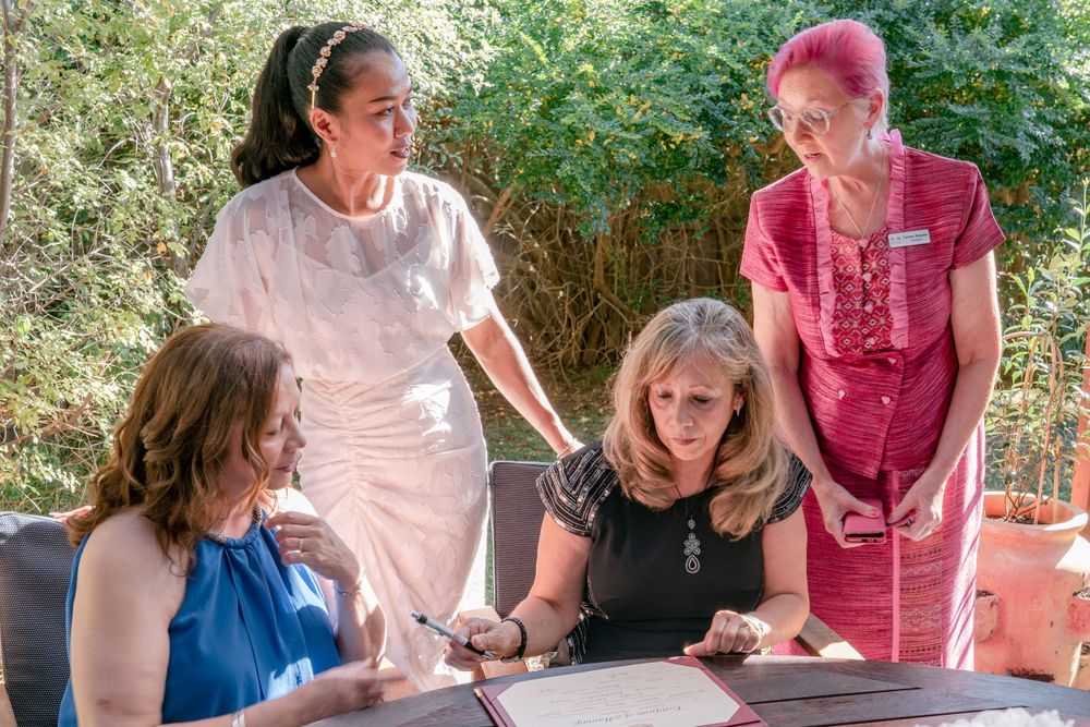 elopement witnesses signing certificate while celebrant in pink and asian bride look on
