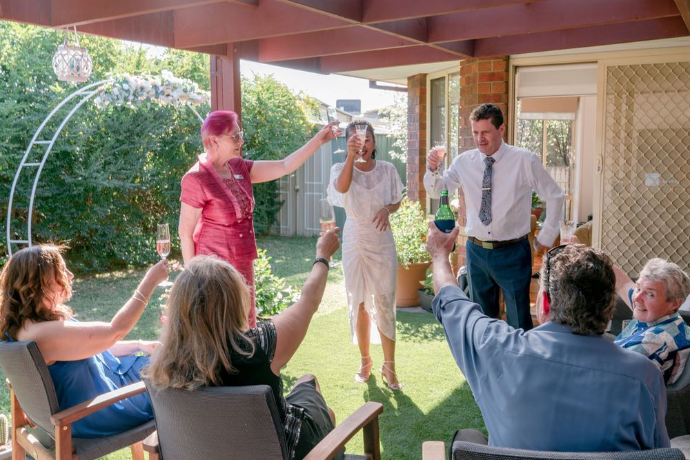 celebrant in pink toasting bride and groom with witnesses backyard elopement