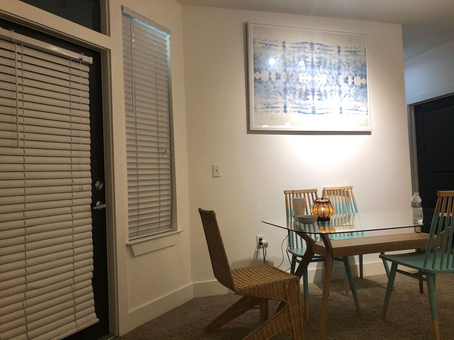 Living room interior with white walls, window blinds, and modern furniture arrangement.