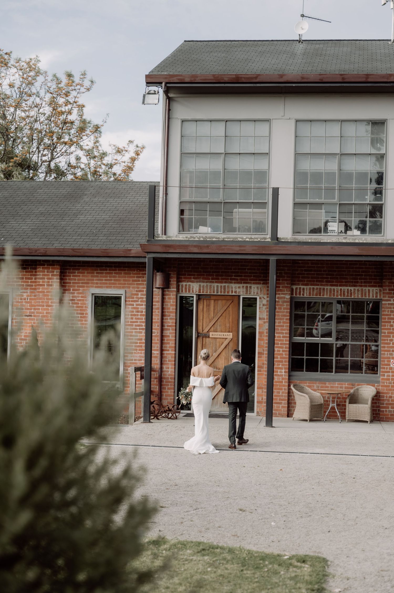 Modern industrial wedding venue with brick exterior and large windows on a cloudy day.