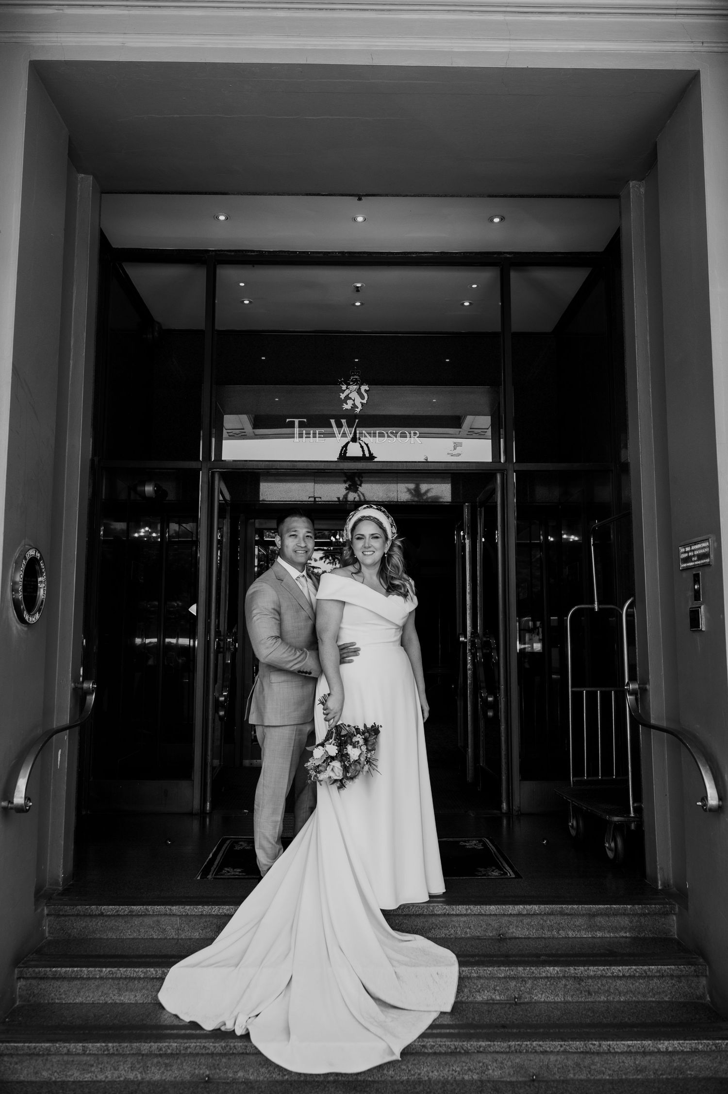 Black and white wedding sequence showing bride and groom entering elegant building entrance with flowing dress.