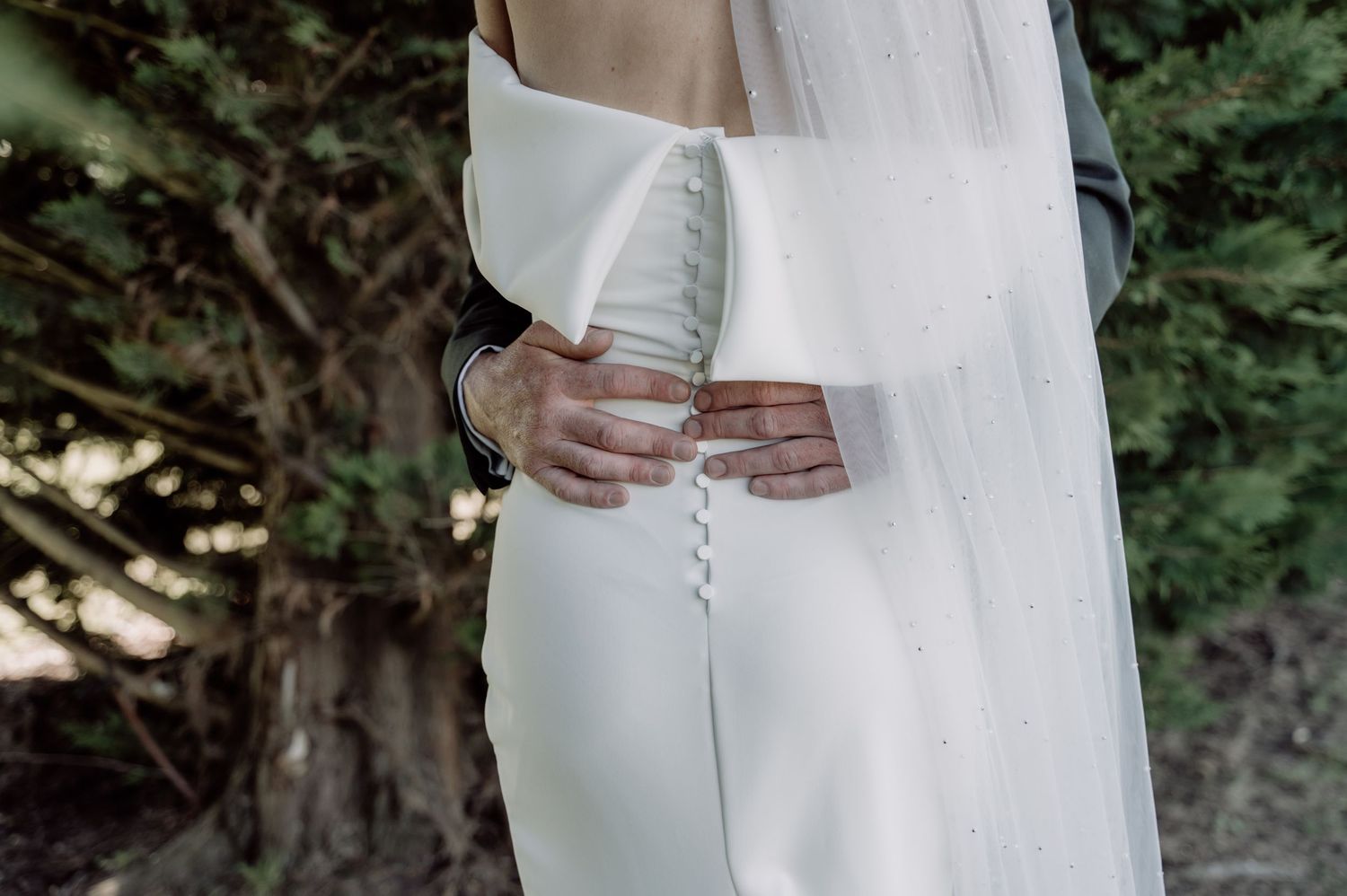 Elegant white long-sleeved dress shown in a photo sequence with delicate details and flowing fabric against greenery.
