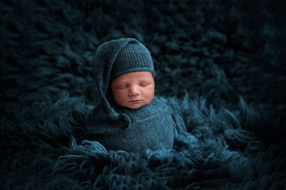 newborn baby wrapped and posed on blue rug