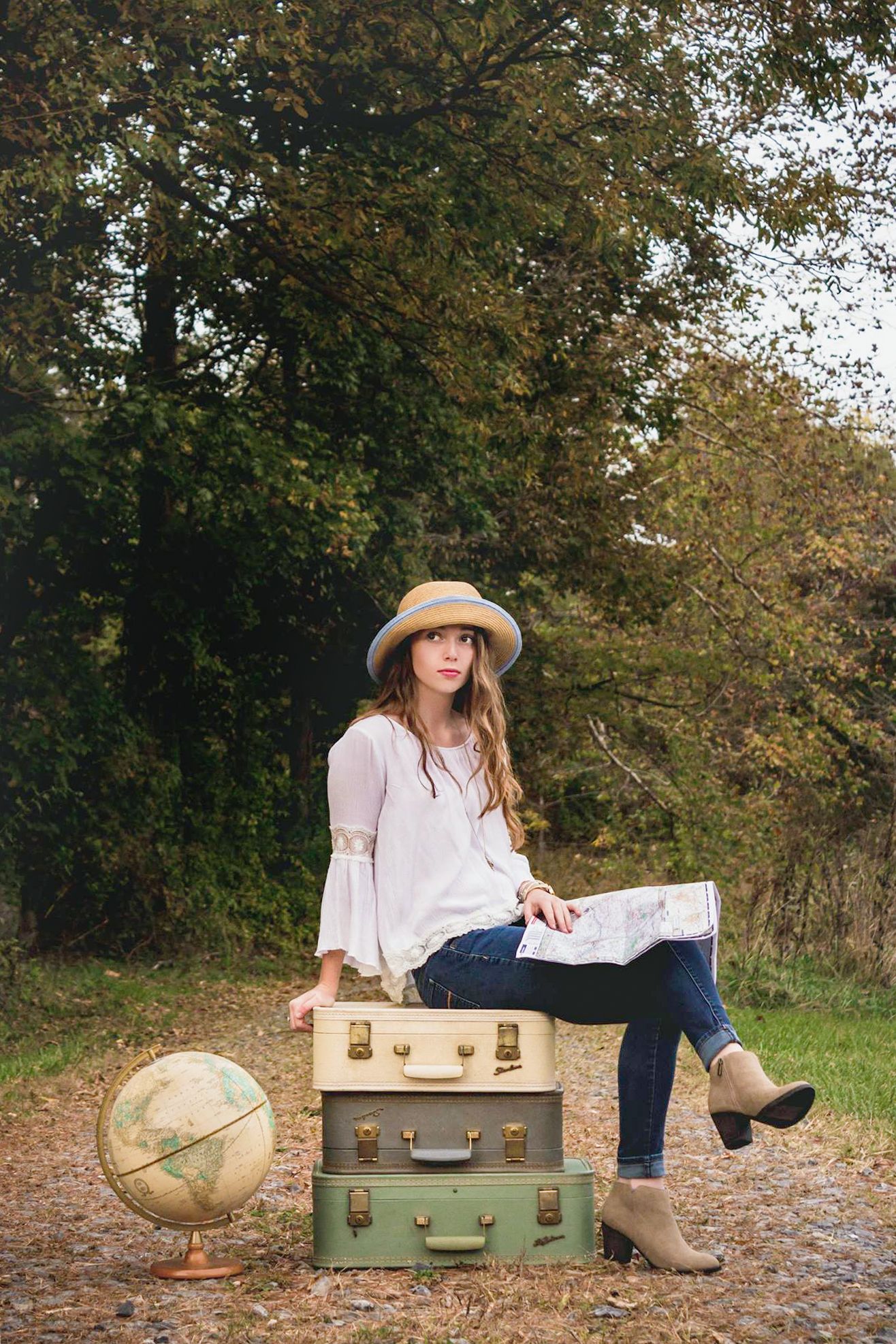 A senior girl sits atop suitcases thinking about the adventure ahead