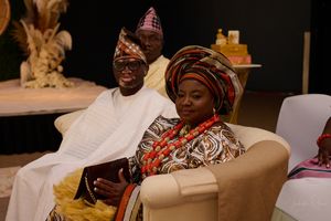 Traditional African wedding guests in formal cultural attire seated at celebration.
