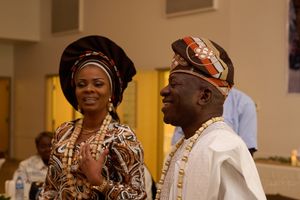 Nigerian wedding celebration with guests in traditional gele headwraps and cultural attire.