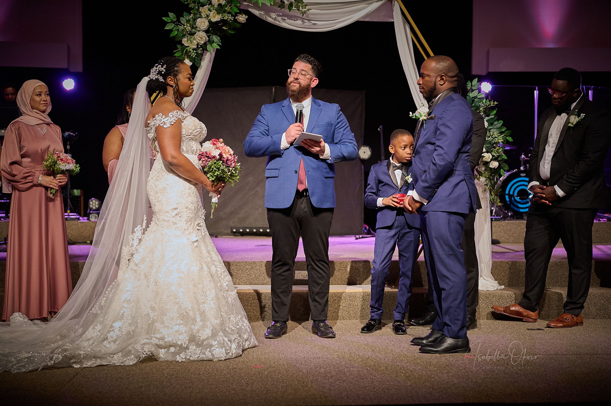 Wedding ceremony under draped arch with couple and officiant at the altar.