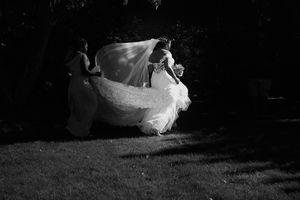 Black and white photo of bride twirling in wedding dress outdoors.