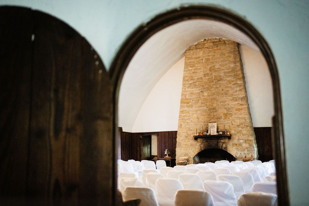 Reception room with white chairs viewed through arched doorway featuring stone fireplace.