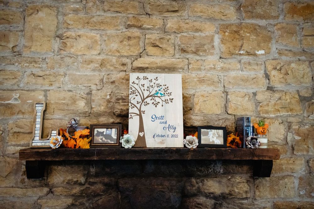 Rustic wooden shelf with wedding decor and family tree artwork mounted on stone wall.