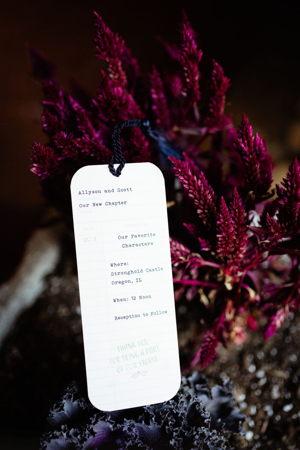 Wedding menu card displayed against vibrant purple flowers with dark background.