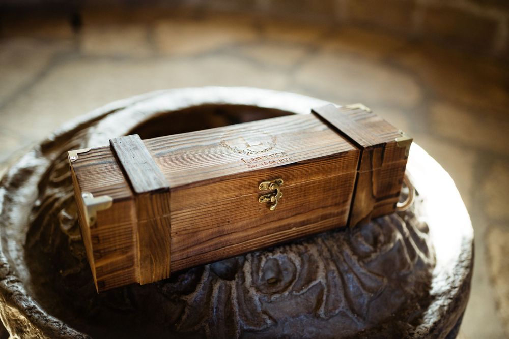 Rustic wooden box with metal clasp photographed on textured surface.