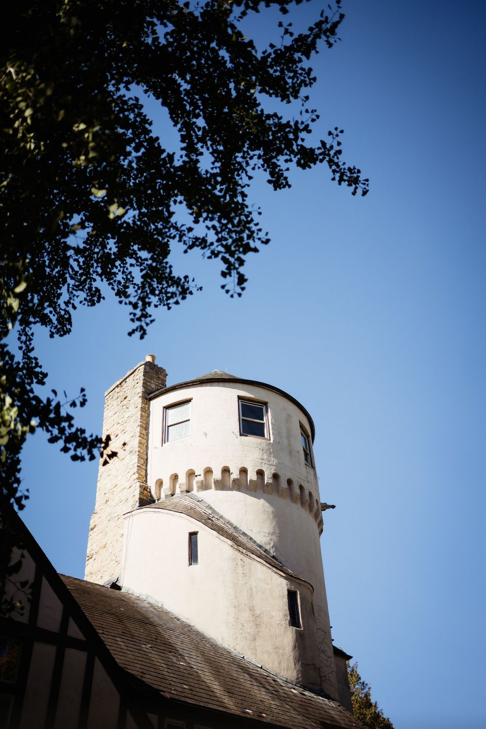 A white cylindrical tower with castle-like features rises against a bright blue sky.