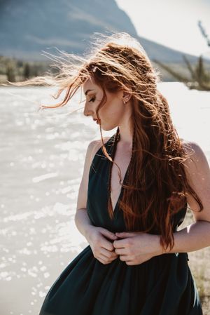 Wind blows through long hair against mountain backdrop in dramatic lighting.