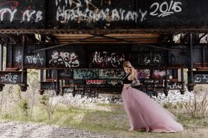 Pink tulle gown contrasts with graffiti-covered urban walls in artistic photo.