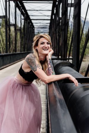 Two-piece pink tulle outfit worn while posing on rustic metal bridge with mountain views.