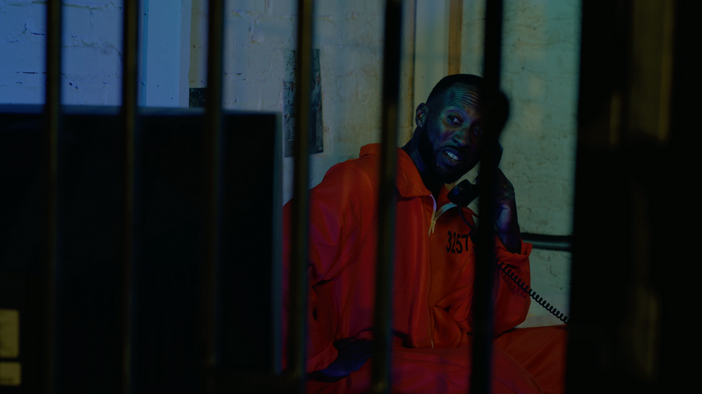 Daunte Moore in jail cell with orange gum suit watching tv in short film video production