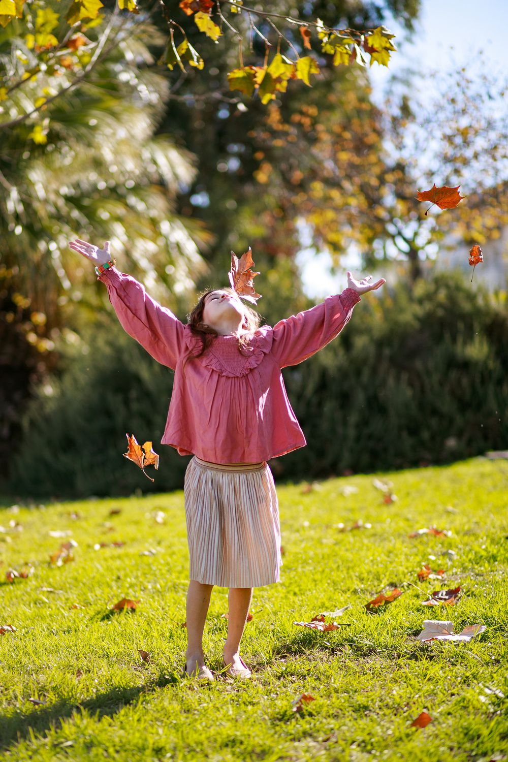 A beautiful picture of a girl in nature throwing leaves up