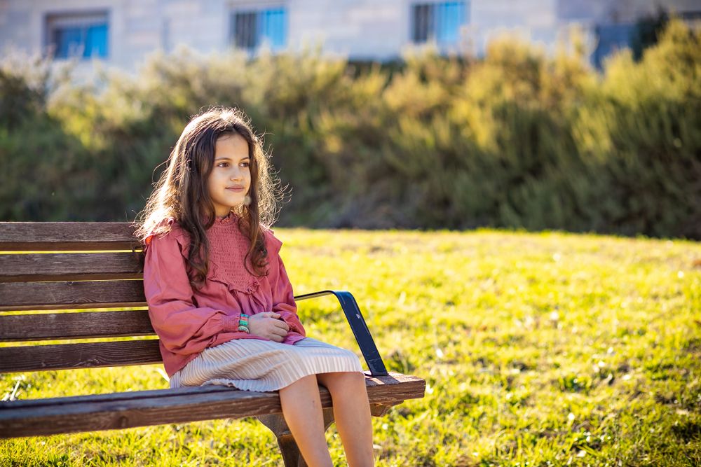 A picture of a girl sitting on the bench in nature