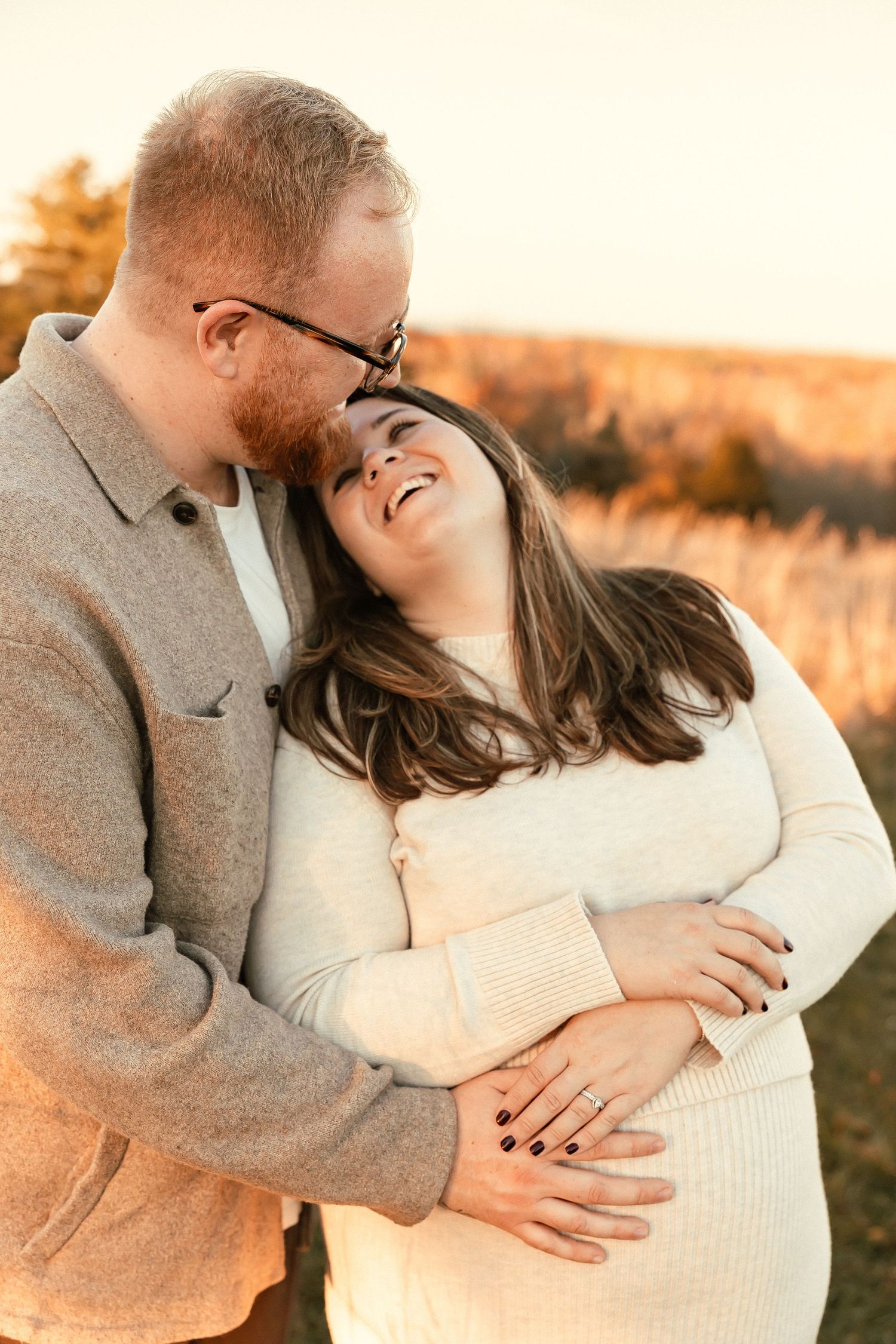 Sunset engagement photo with couple embracing in golden light.