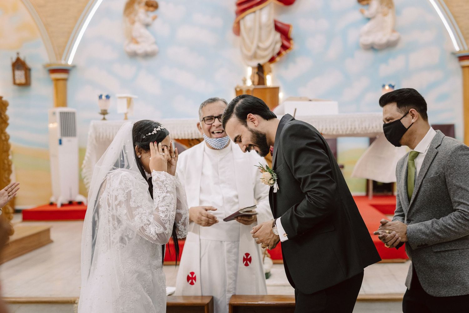 A joyful moment during the wedding ceremony with guests looking on in a decorated church.