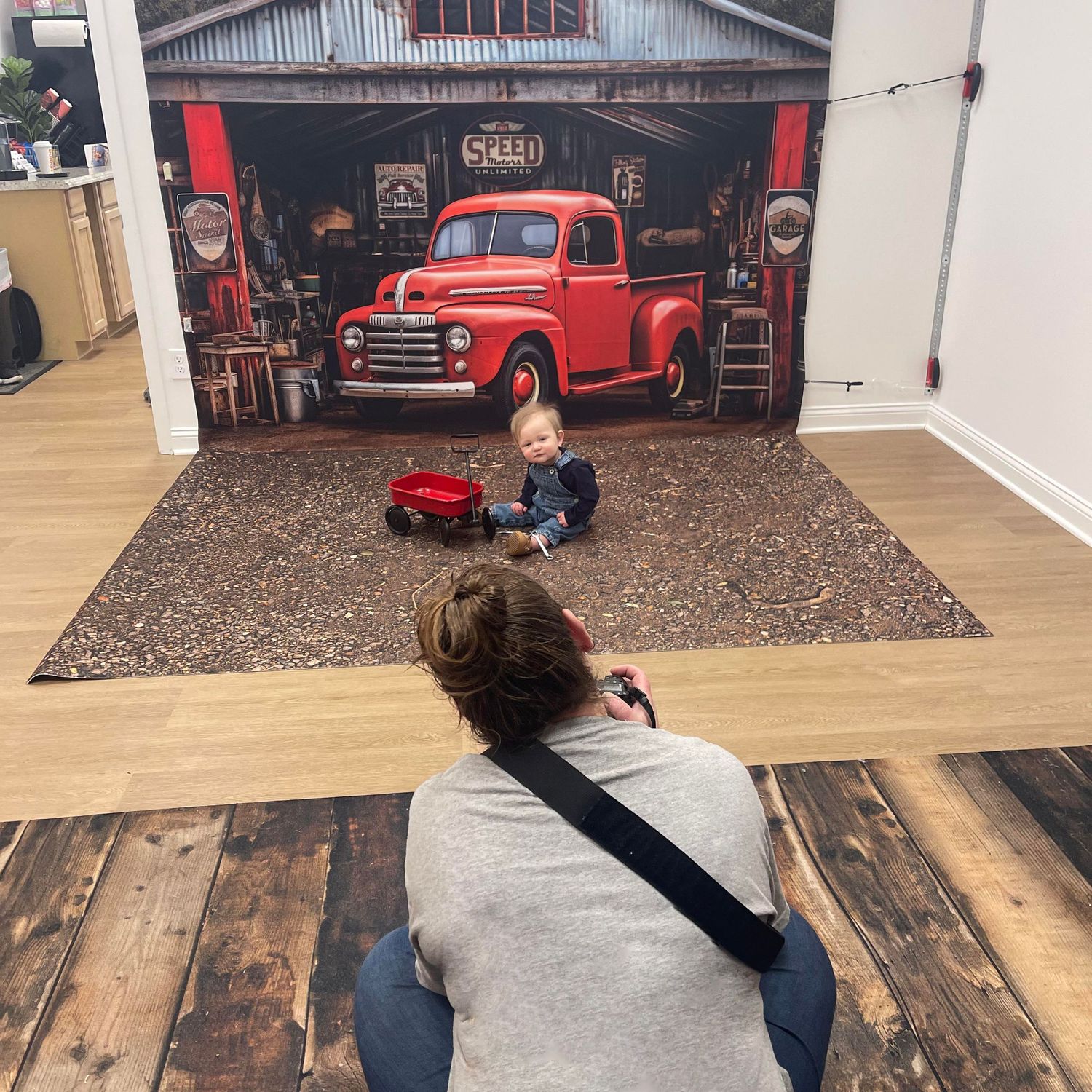 Photographer capturing image of child with vintage red truck backdrop.