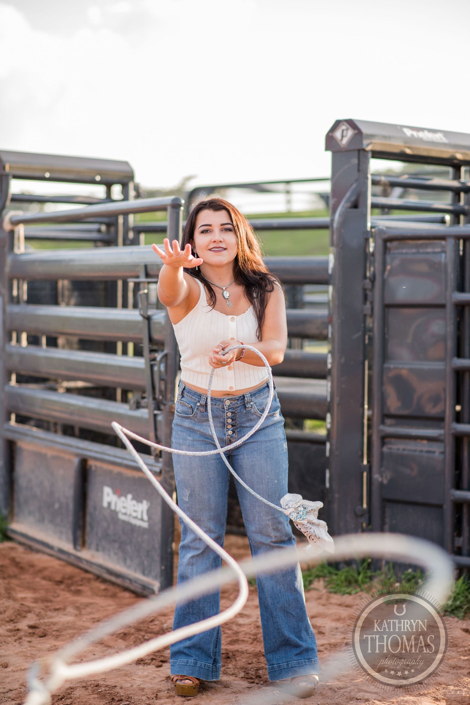 A western-themed portrait with a lasso rope by metal horse stalls.