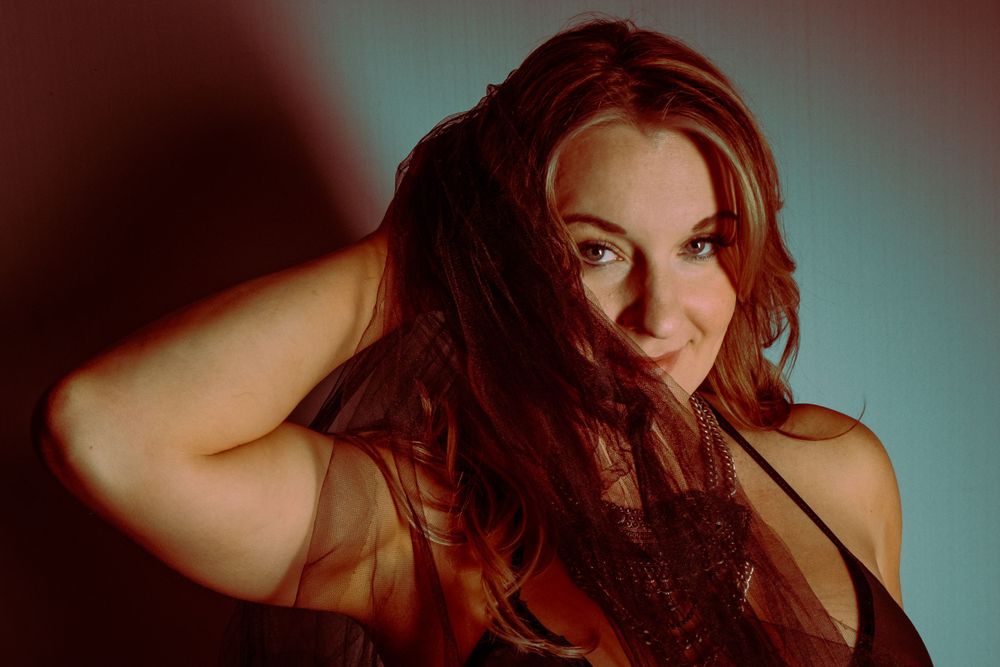 Moody portrait against blue backdrop with dramatic lighting.