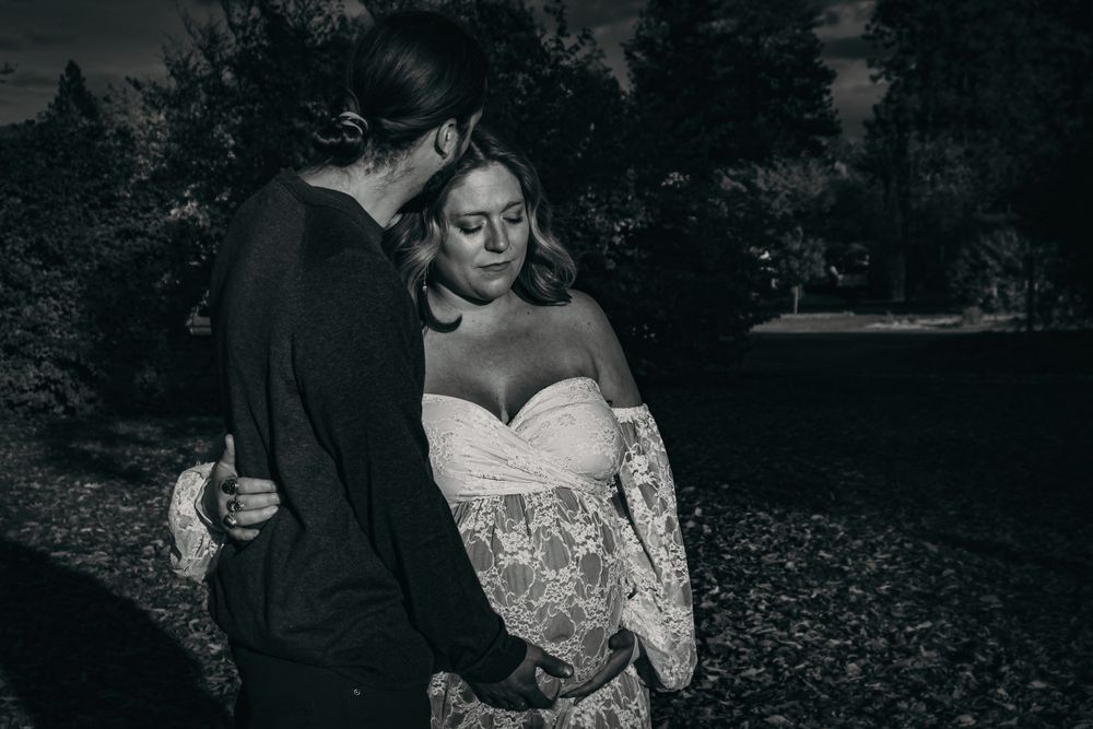 A romantic black and white wedding photo of a couple sharing an intimate moment among fallen leaves.