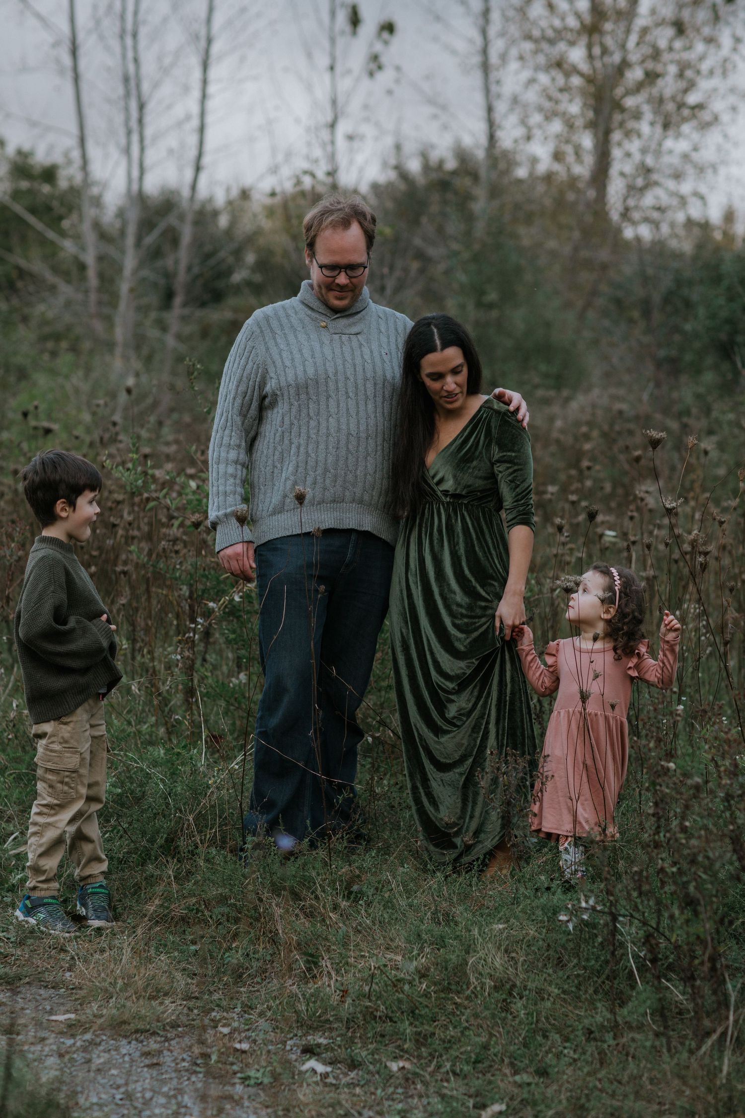 A family of four poses together on a forest path during fall.