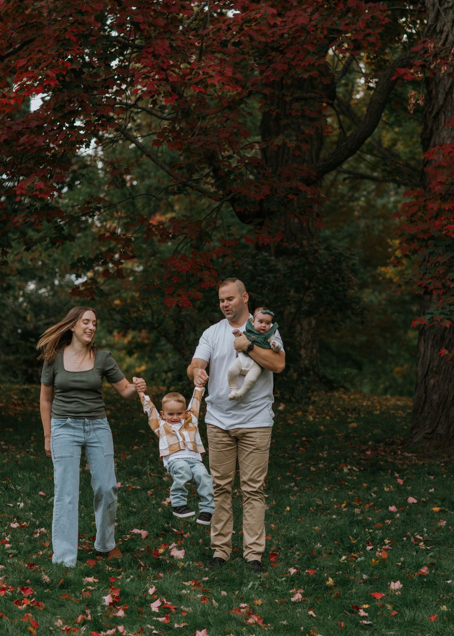 Family walking together through park with red maple trees in fall.