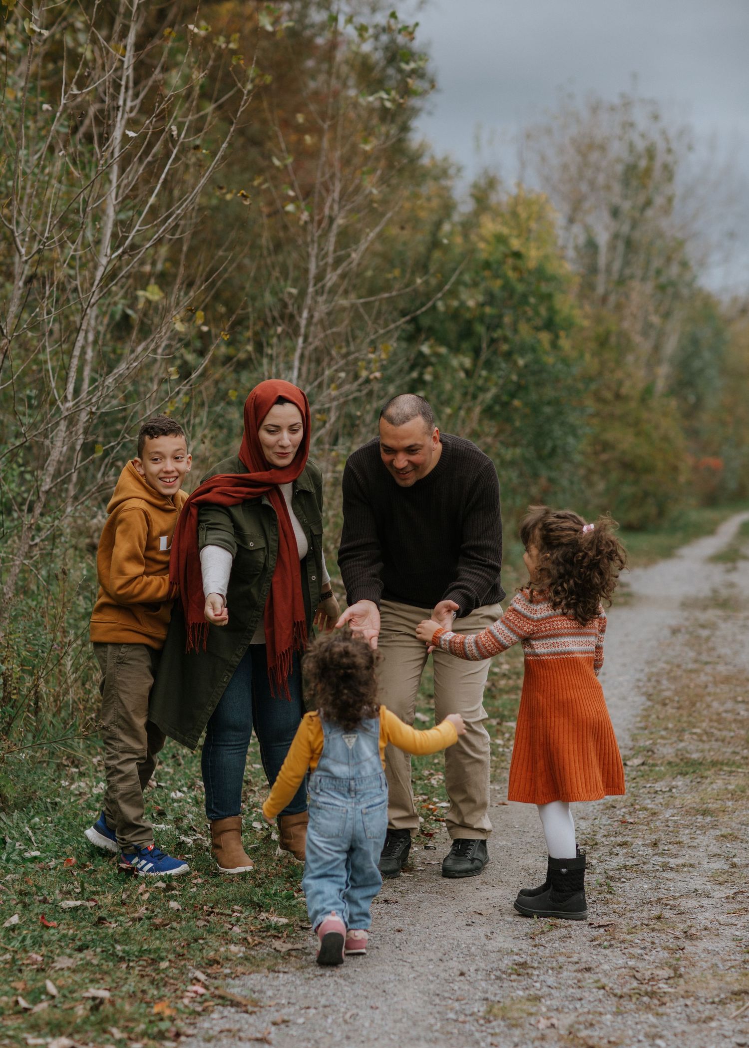 A family enjoys an autumn walk together on a wooded trail.