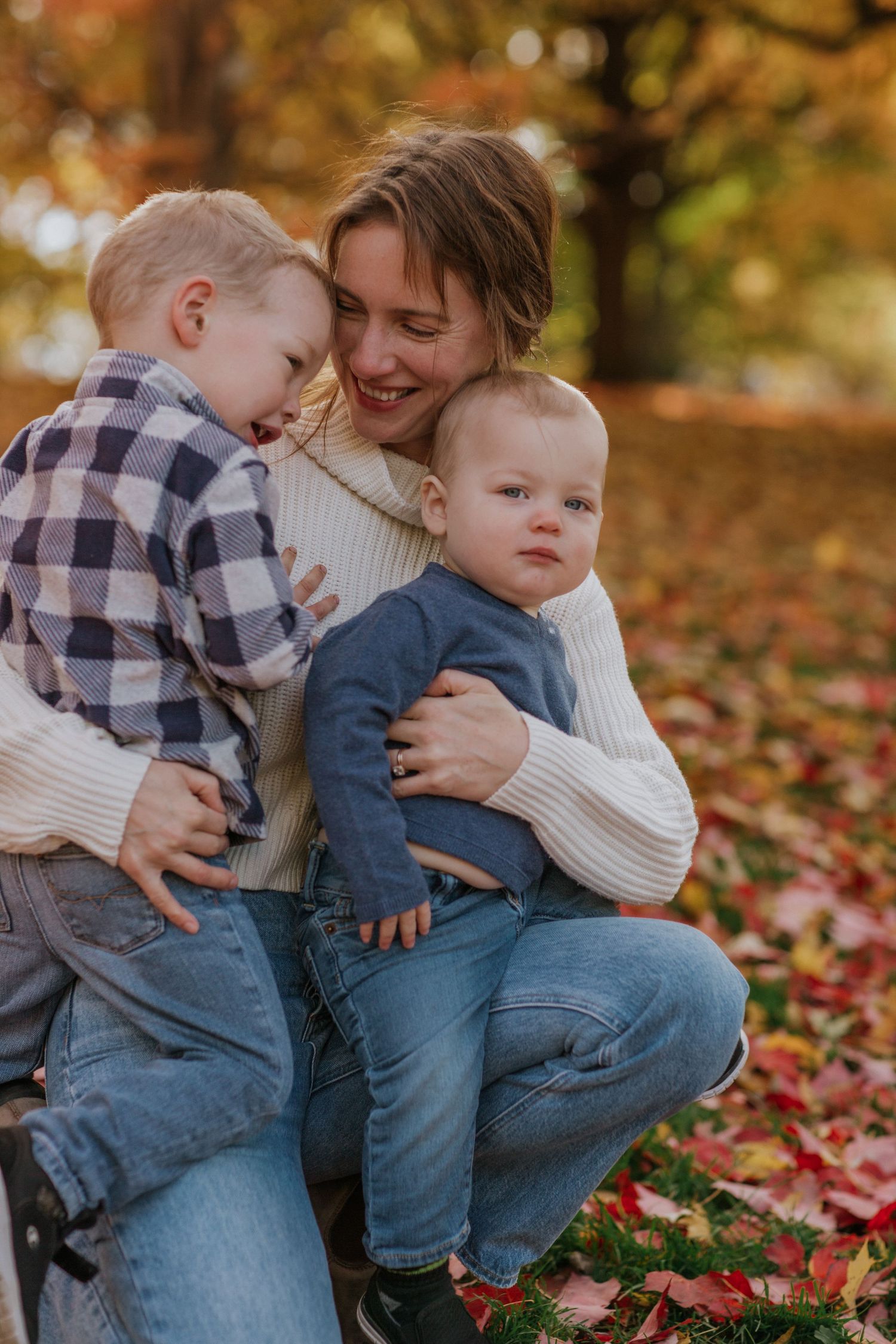 Mom and kids, smiling having fun and immersed in the beauty of vibrant fall colours near Ottawa, ON.