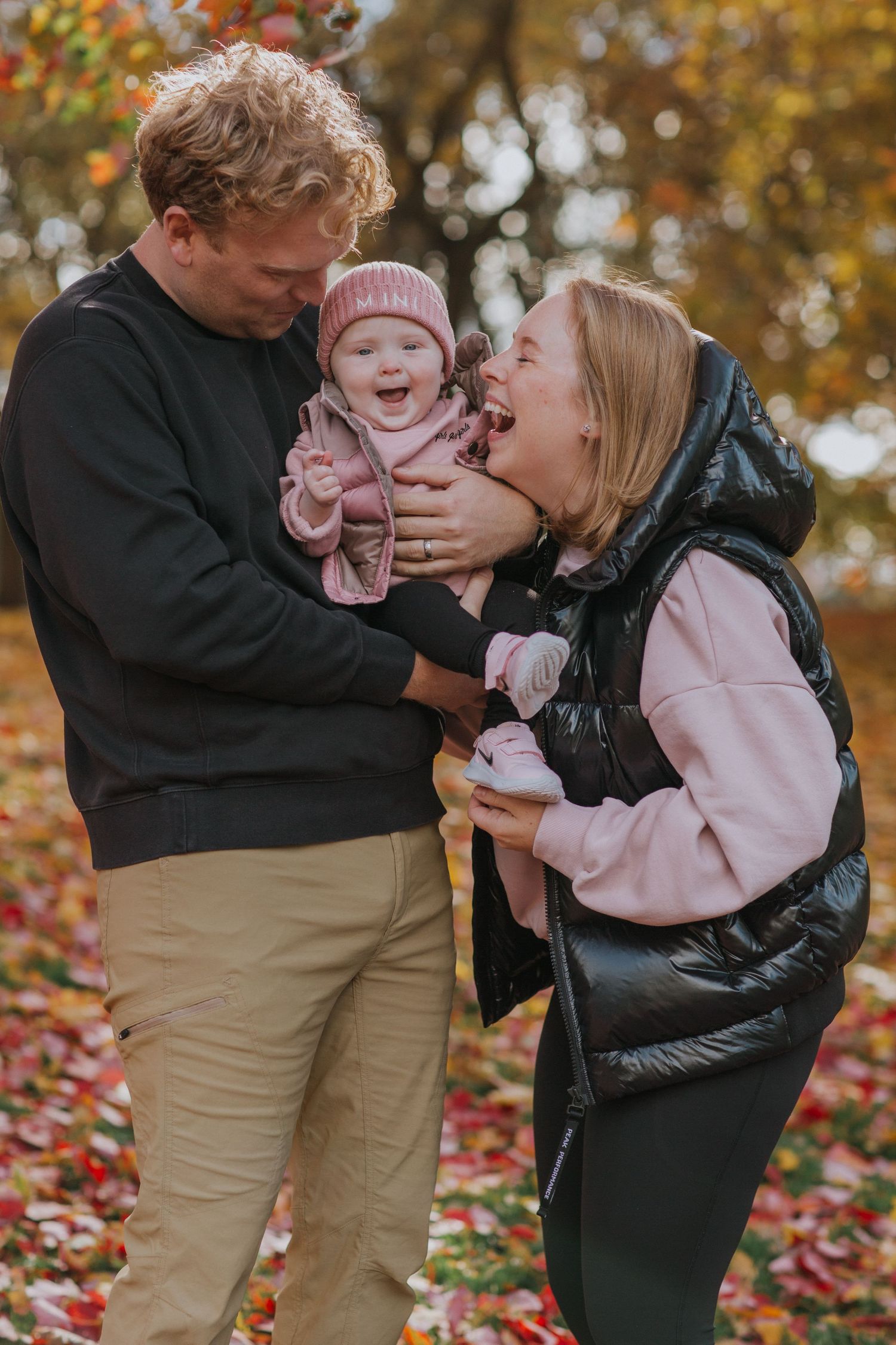 Family shares tender moments together during autumn photoshoot with fallen leaves in the background.