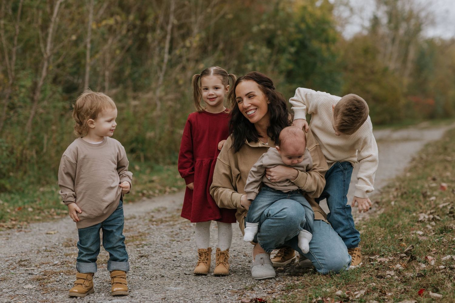 A family gathers on a dirt path surrounded by autumn trees and foliage.