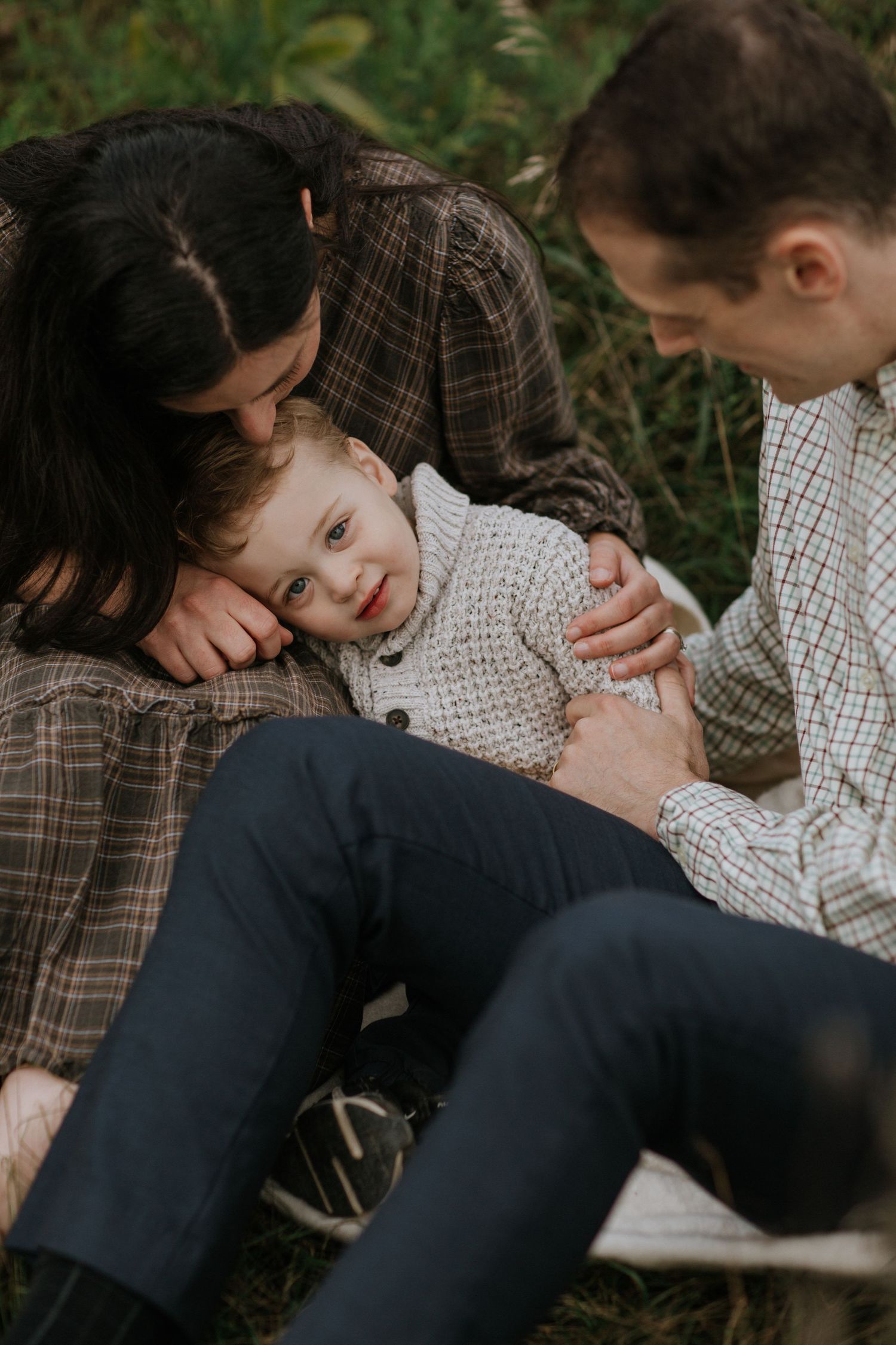 An intimate family moment captured outdoors with everyone laying in the grass together.
