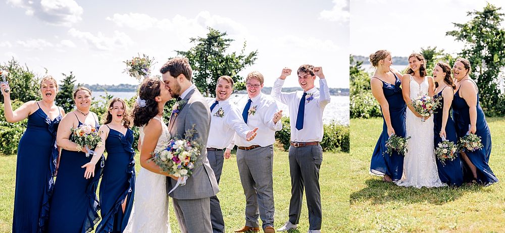 Wedding party in navy blue and gray attire poses on a grassy oceanside cliff under blue skies.